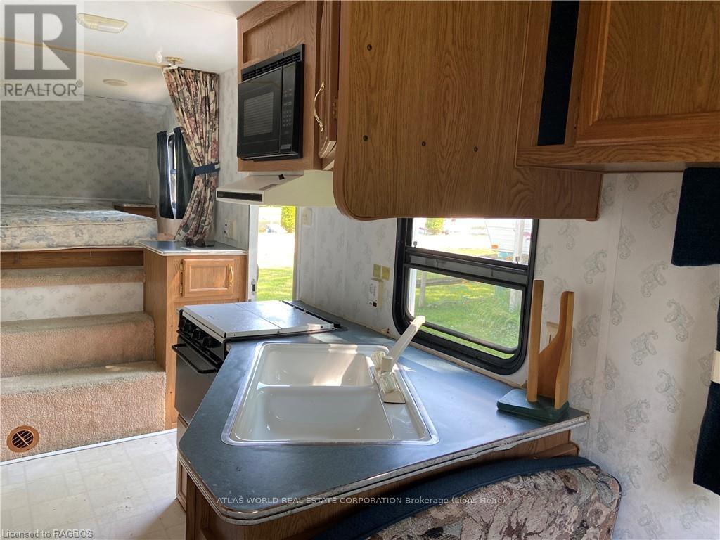 A kitchen area with a sink, stove, and microwave.