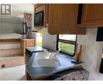 A kitchen area with a sink, stove, and microwave.