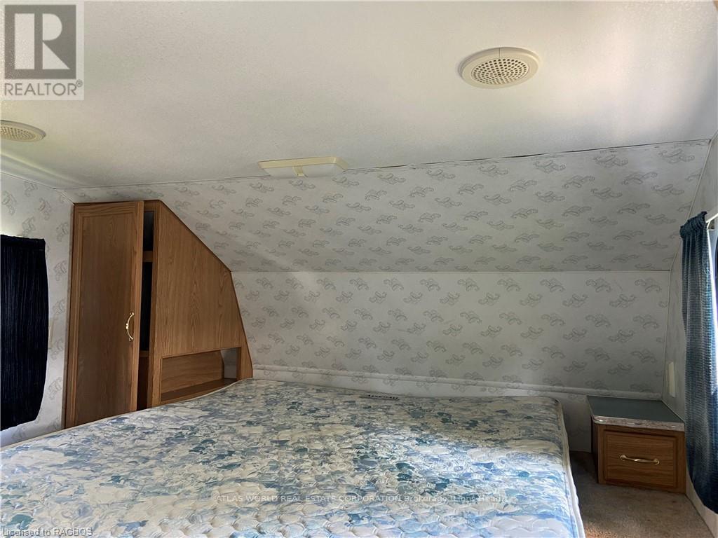 A bedroom with a patterned wallpaper and a bed with a blue comforter.