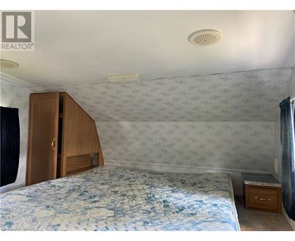 A bedroom with a patterned wallpaper and a bed with a blue comforter.