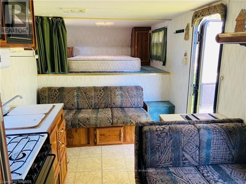 A living room with a couch and a bed in a trailer.
