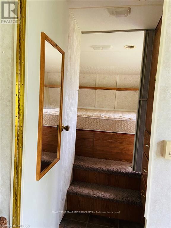 A bedroom with a bed and stairs leading to the second floor.
