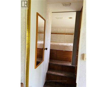 A bedroom with a bed and stairs leading to the second floor.