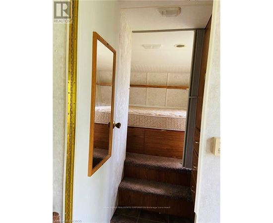 A bedroom with a bed and stairs leading to the second floor.