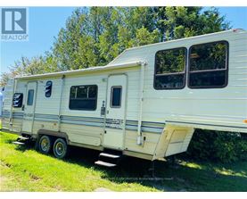 A white trailer is parked in a grassy area.