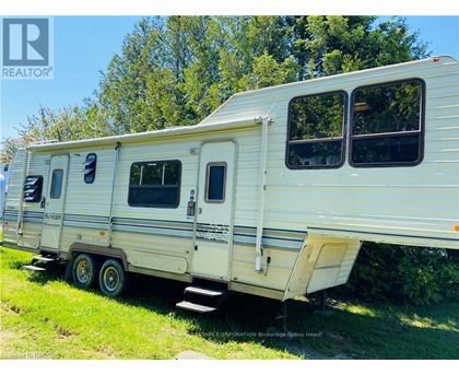 A white trailer is parked in a grassy area.
