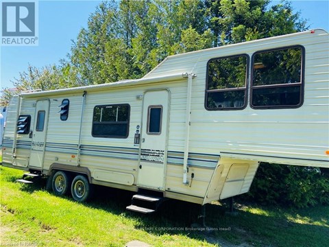 A white trailer is parked in a grassy area.