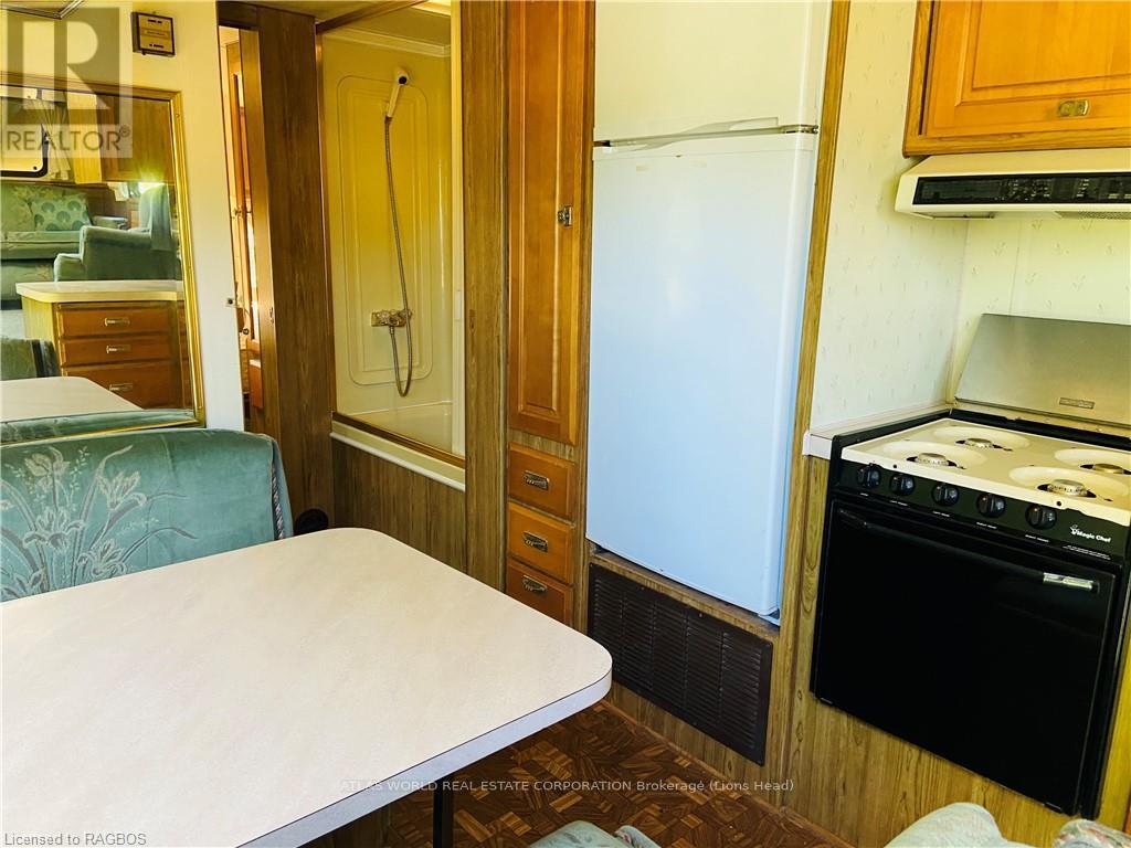 A small kitchen with a fridge, oven and a table.