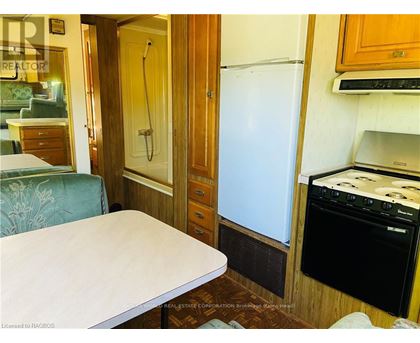 A small kitchen with a fridge, oven and a table.