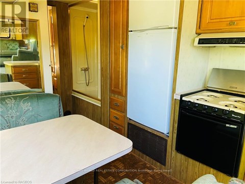 A small kitchen with a fridge, oven and a table.