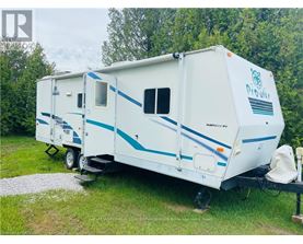 A white and blue RV is parked in a grassy area.