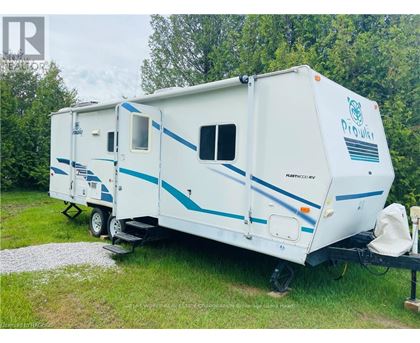 A white and blue RV is parked in a grassy area.