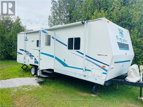 A white and blue RV is parked in a grassy area.