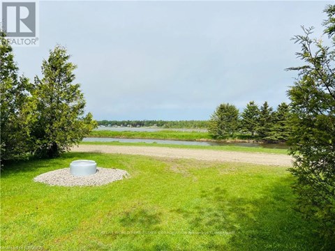A well-maintained lawn with a pond and trees in the distance.