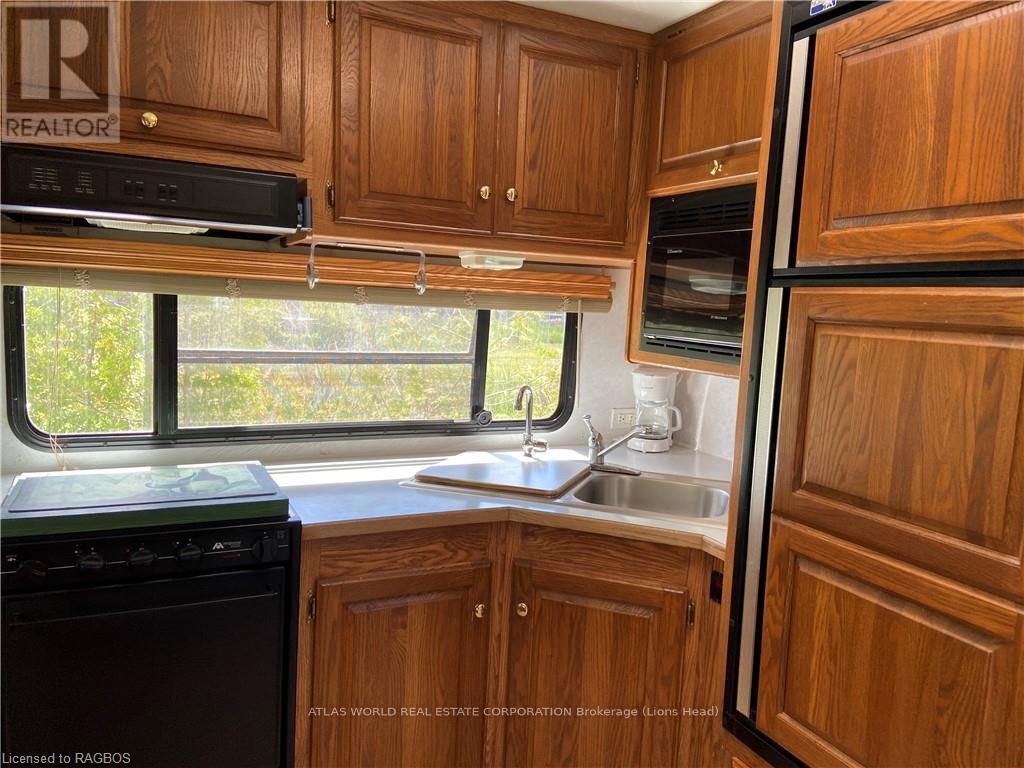 A kitchen with wooden cabinets and a black dishwasher.