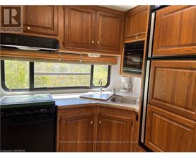 A kitchen with wooden cabinets and a black dishwasher.