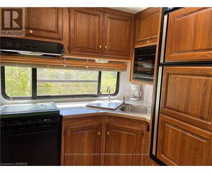 A kitchen with wooden cabinets and a black dishwasher.