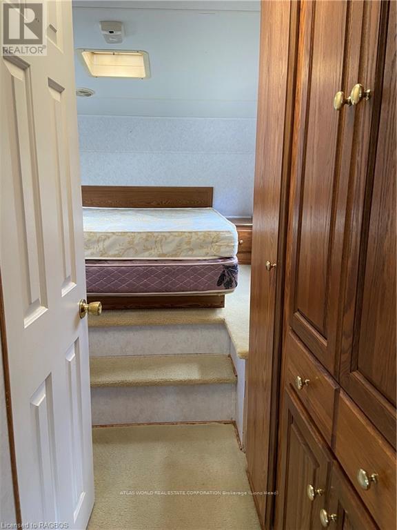 A bedroom with a bed, stairs, and a wooden wardrobe.
