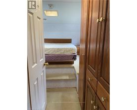 A bedroom with a bed, stairs, and a wooden wardrobe.