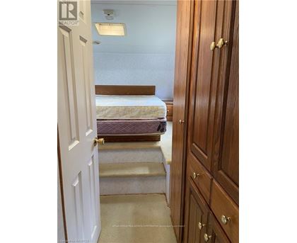 A bedroom with a bed, stairs, and a wooden wardrobe.