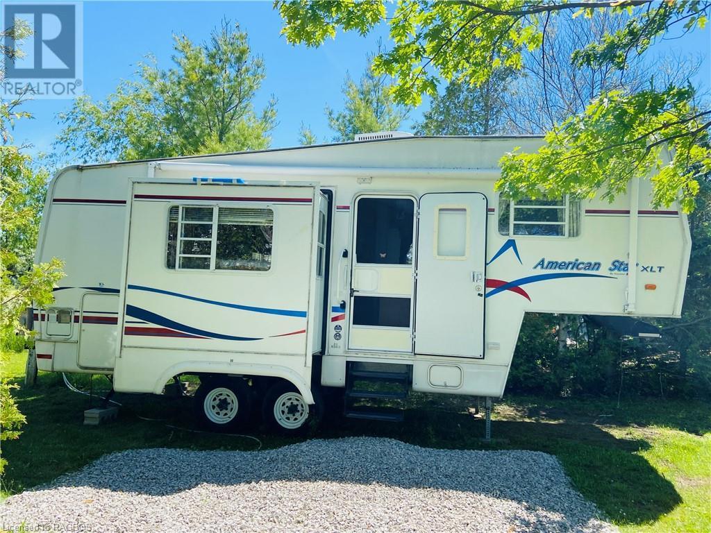 A white RV with blue and red stripes is parked in a grassy area.