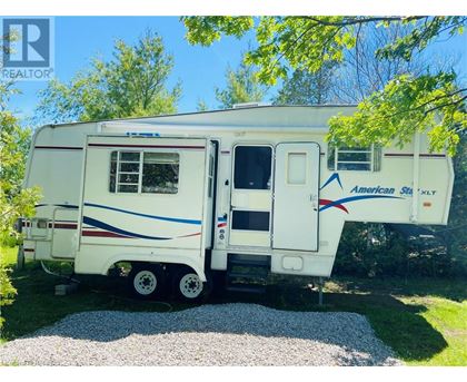 A white RV with blue and red stripes is parked in a grassy area.