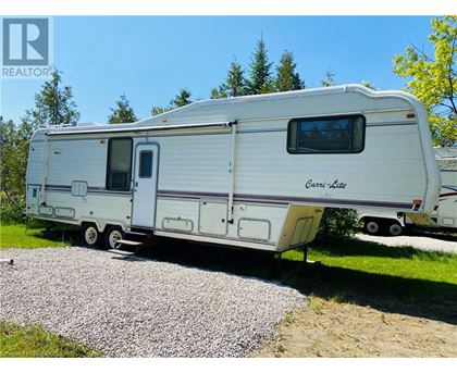 A white RV is parked on a gravel area.