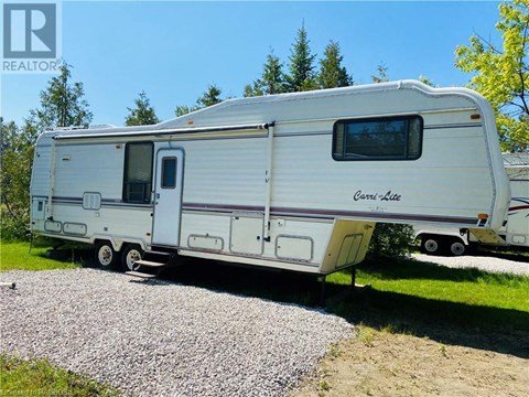 A white RV is parked on a gravel area.