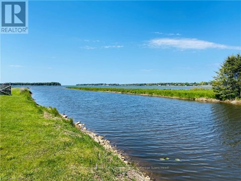 A river flows through a grassy area with a clear blue sky above.
