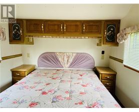 A bedroom with a bed, nightstands, and a wooden cabinet above the bed.