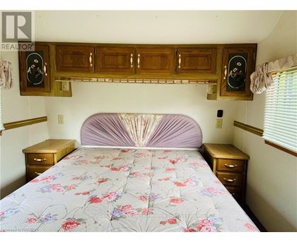 A bedroom with a bed, nightstands, and a wooden cabinet above the bed.