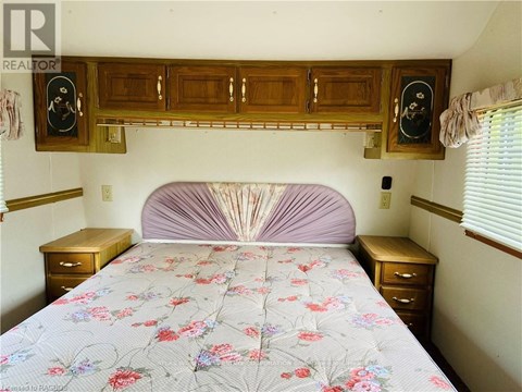 A bedroom with a bed, nightstands, and a wooden cabinet above the bed.