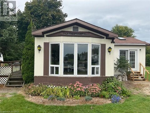 A small house with a brown roof and a garden in front.