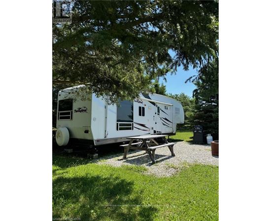 A white RV is parked in a grassy area.