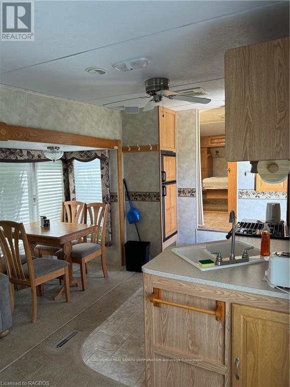 A kitchen area with a sink, wooden chairs and cabinets.