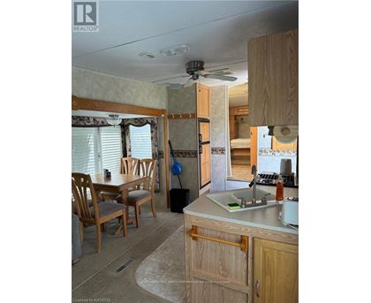 A kitchen area with a sink, wooden chairs and cabinets.