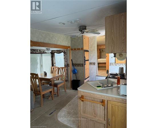 A kitchen area with a sink, wooden chairs and cabinets.