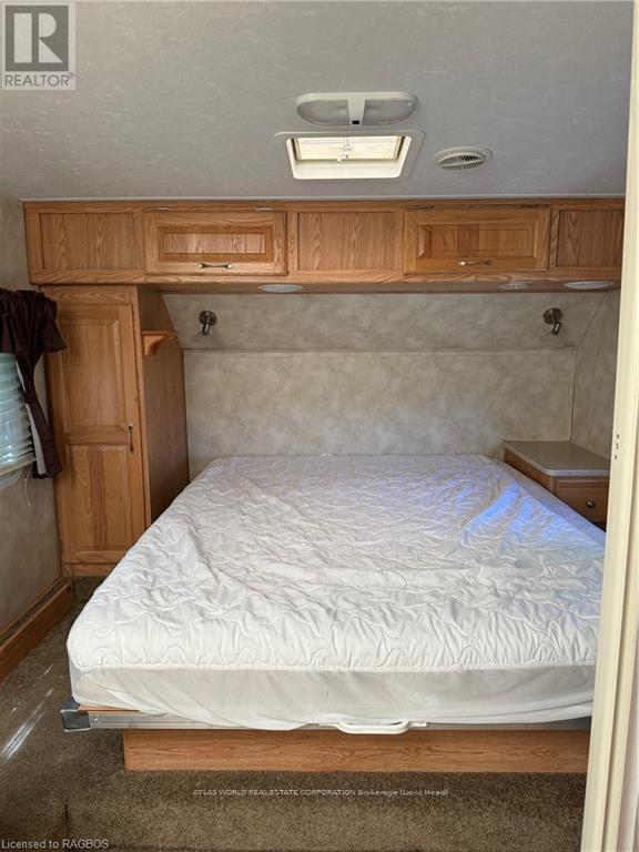 A bedroom with a bed, wooden cabinets, and a window.