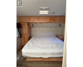 A bedroom with a bed, wooden cabinets, and a window.
