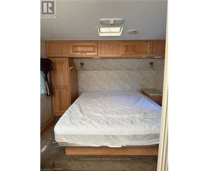 A bedroom with a bed, wooden cabinets, and a window.