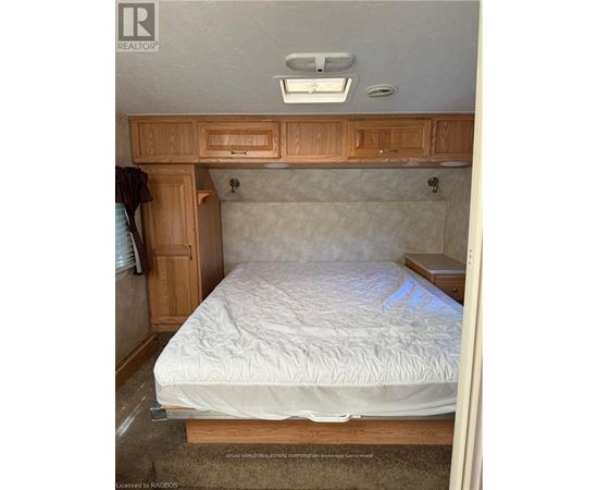 A bedroom with a bed, wooden cabinets, and a window.