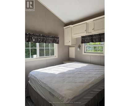A bedroom with a bed, window, and cupboard.