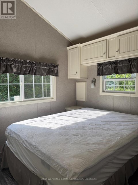 A bedroom with a bed, window, and cupboard.