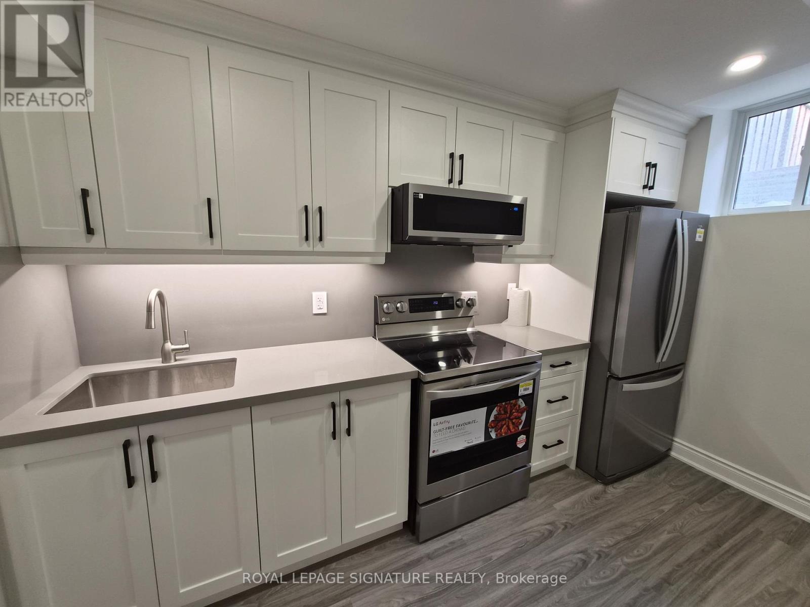 A kitchen with white cabinets and a stainless steel refrigerator.