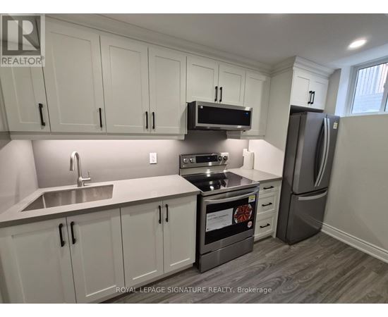 A kitchen with white cabinets and a stainless steel refrigerator.