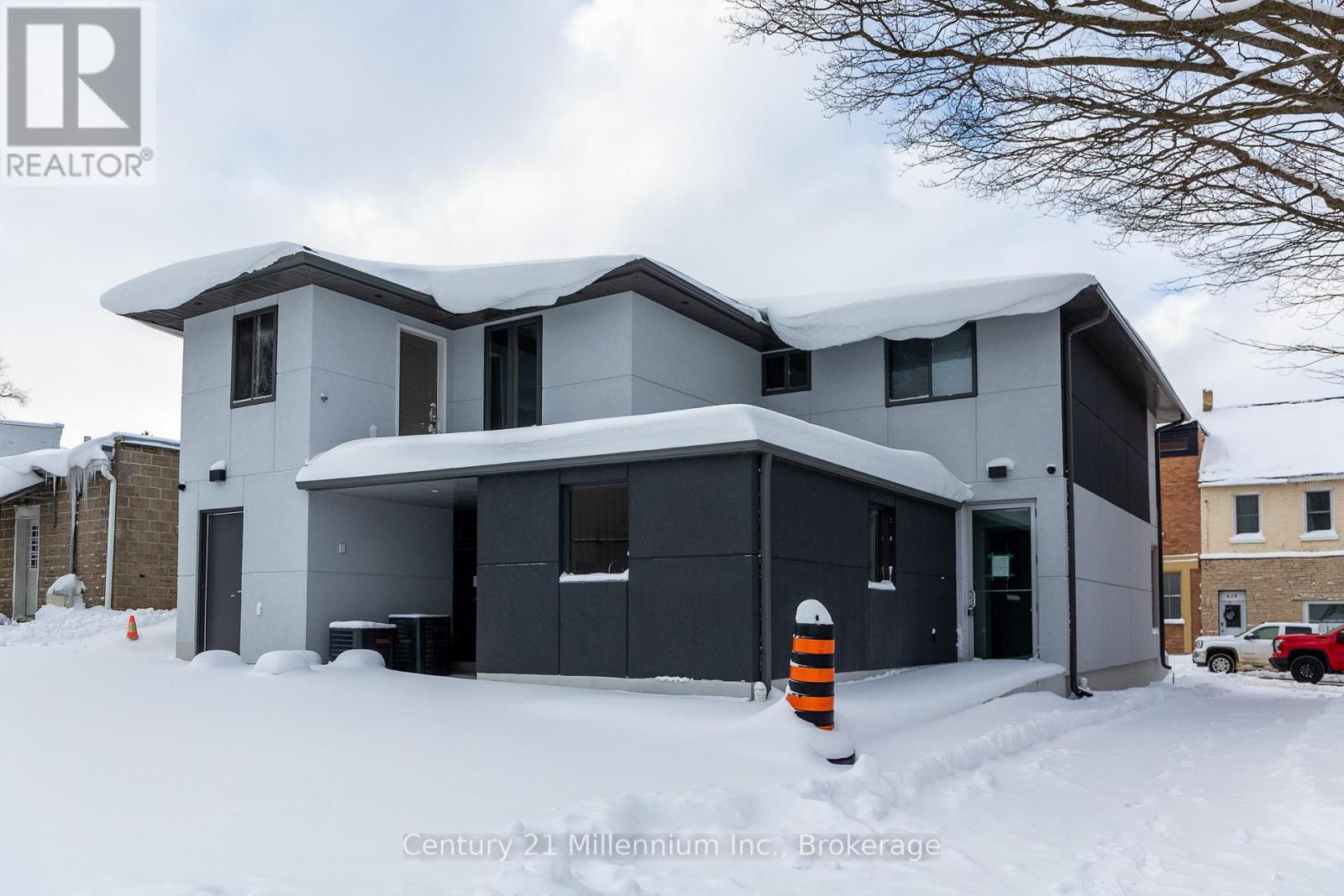 A house with snow on the ground and a red truck in the background.