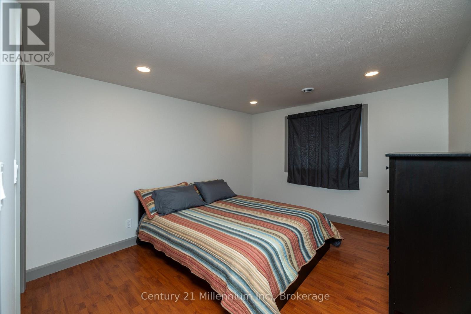 A bedroom with a bed and a window with a black curtain.