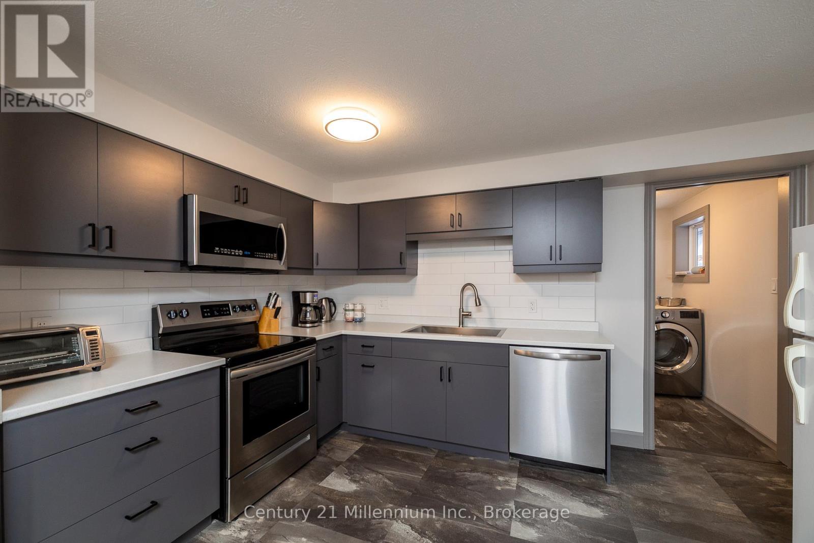 A kitchen with grey cabinets and stainless steel appliances.