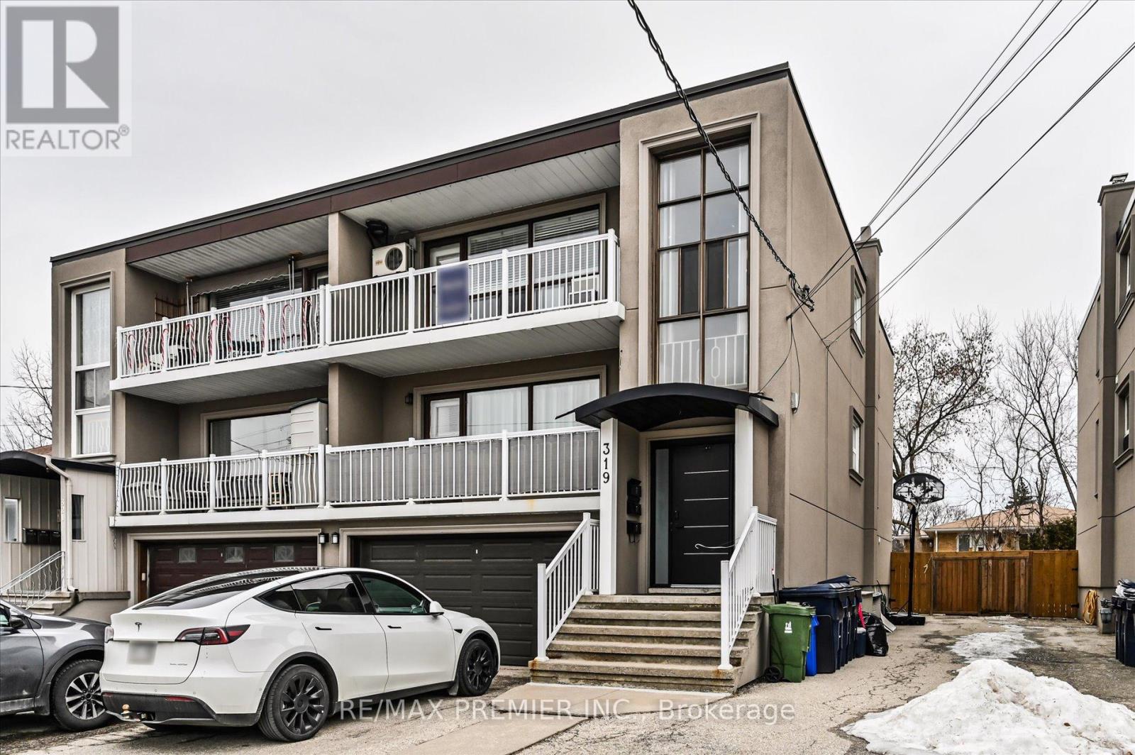 A white car is parked in front of a two-story building.