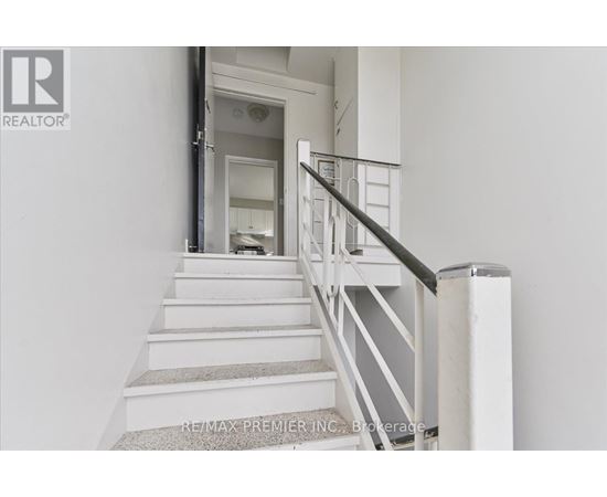 A staircase with a metal railing and a carpeted runner.